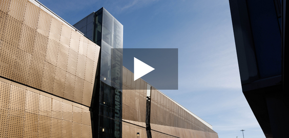 Modern building with glass tower, against a blue sky. 