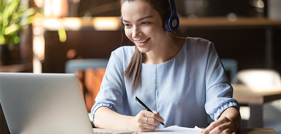 woman smiling at laptop making notes