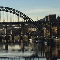Image of Tyne Bridge at sunset with reflections on water.