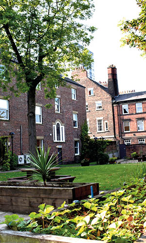 Garden with a lawn, trees and benches, surrounded by buildings