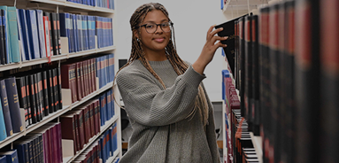 Girl pulling book out of bookshelf and smiling