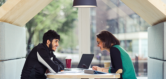 a group of people sitting at a table using a laptop