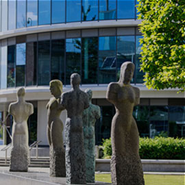 figurative stone statues in a row with glass computing building in background