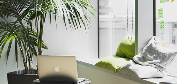 a laptop computer sitting on top of a bed next to a window
