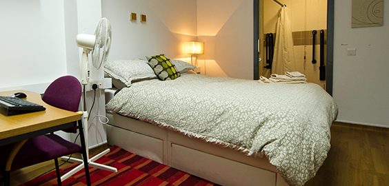 Bedroom with a bed, fan, desk and computer 