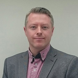 a man wearing a suit and tie smiling at the camera