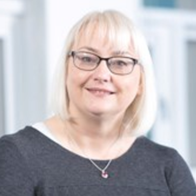 a woman wearing glasses and smiling at the camera