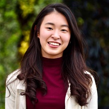Alumni smiling while wearing red top and white jacket