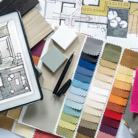 A collection of design materials, including fabric swatches, architectural sketches, wooden samples, and small tiles, arranged on a table.