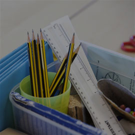 Image of education supplies consisting of pencils in a cup and rulers within box