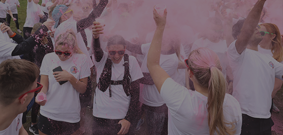 Students standing in a cloud of pink powder from the colour run