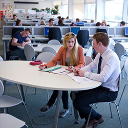 two people sat at a desk talking